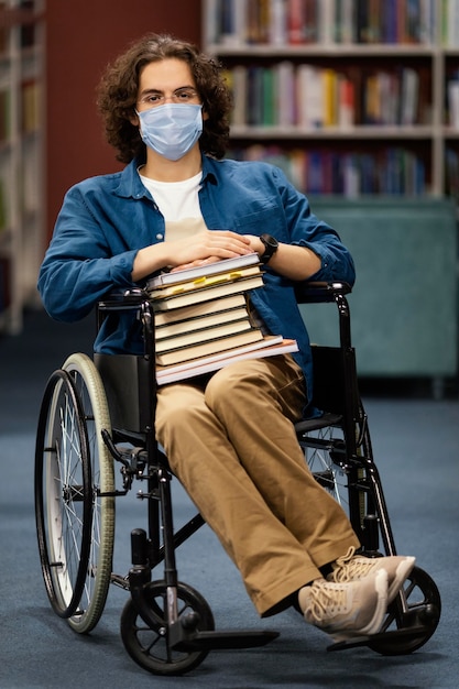 Niño en silla de ruedas sosteniendo un montón de libros