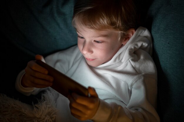 Niño con smartphone en la cama por la noche