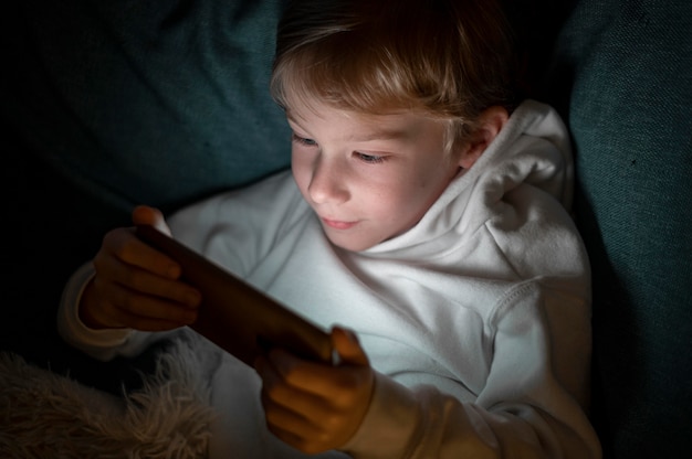 Niño con smartphone en la cama por la noche