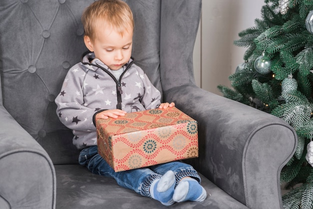 Niño en sofá con caja de regalo