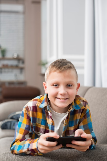 Niño en sofá usando smartphone