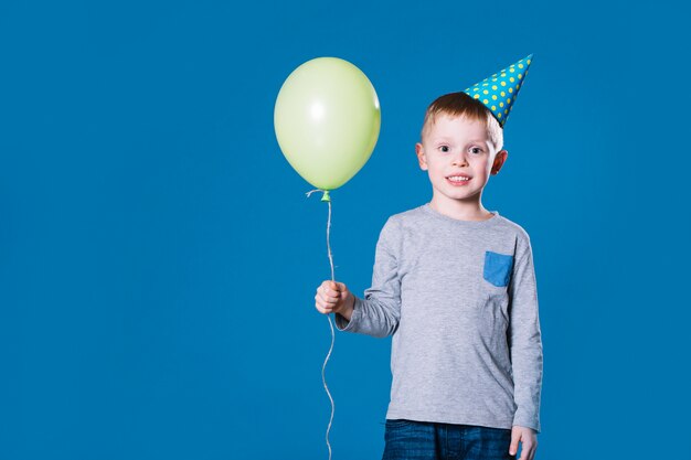 Niño con sombrero de fiesta con globo