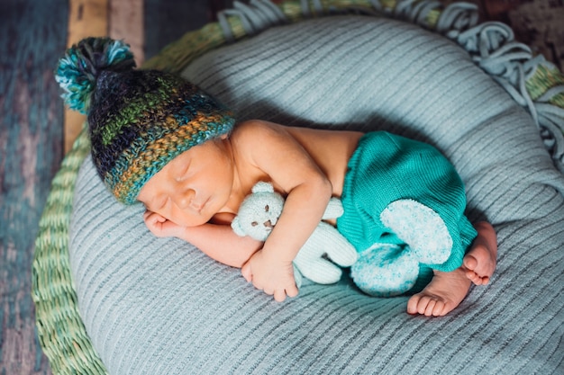 Niño con sombrero hecho punto duerme en almohada azul grande