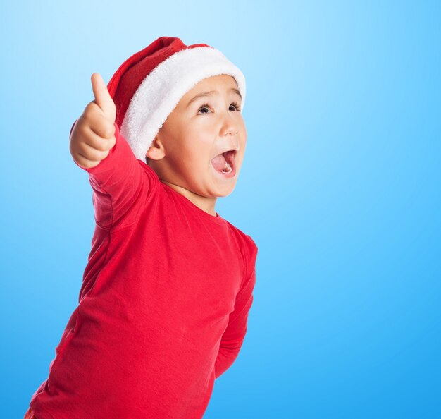 Niño con el sombrero de papa noel y el pulgar levantado