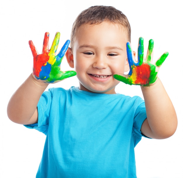 Niño sonriendo con las manos llenas de pintura