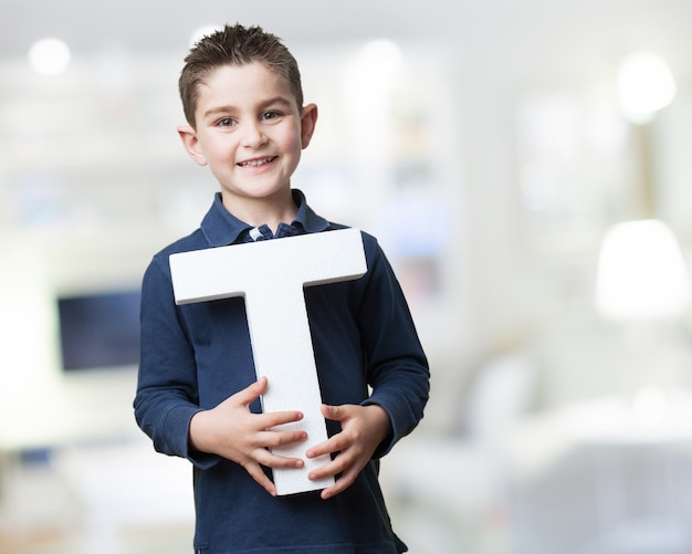 Foto gratuita niño sonriendo mientras sujeta la letra 