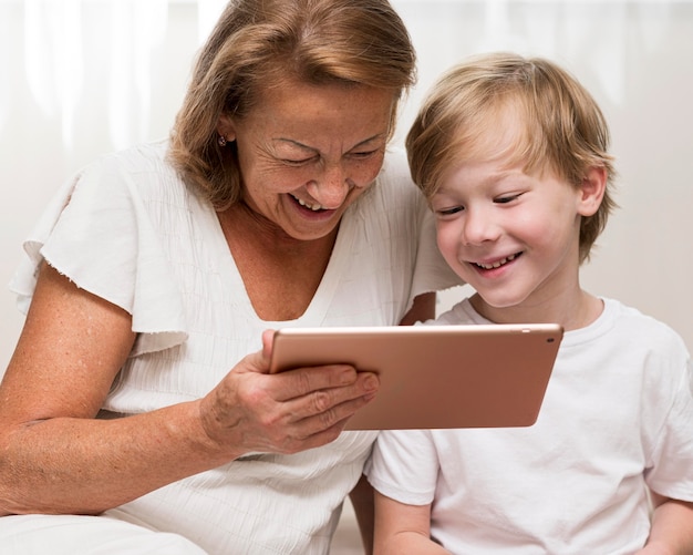 Niño sonriente y abuela con tableta