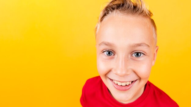 Niño sonriente de alto ángulo con fondo amarillo