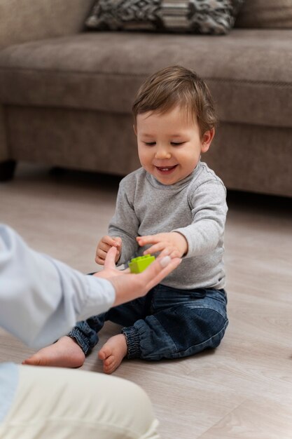 Niño sonriente de alto ángulo sentado en el piso