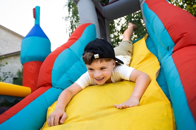 Niño sonriente de ángulo bajo jugando en la casa de rebote