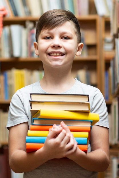 Niño sonriente de ángulo bajo con pila de libros