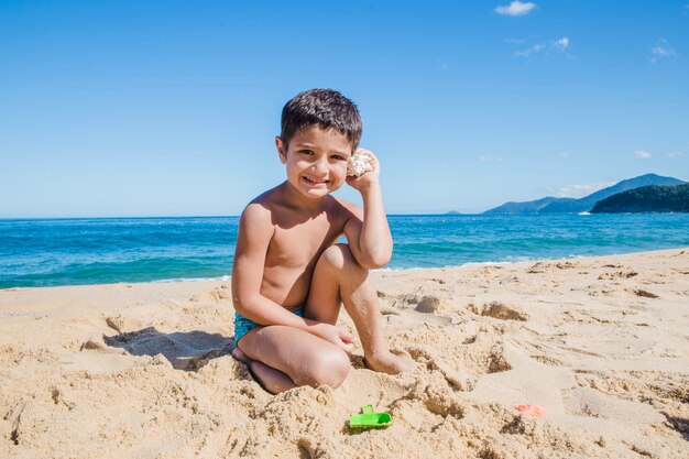 Niño sonriente con concha en verano