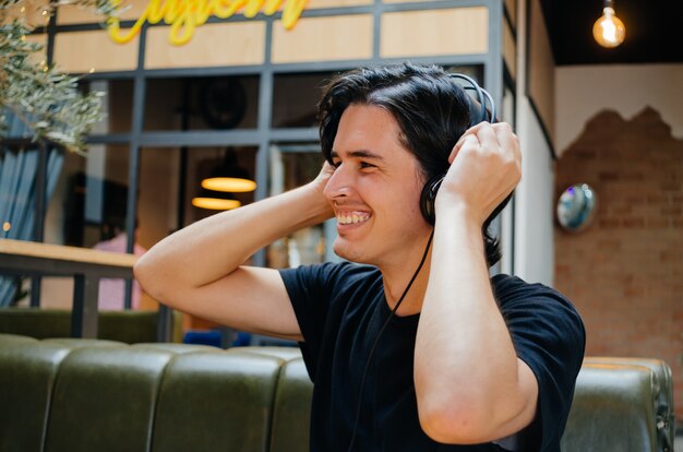 Niño sonriente escuchando música con auriculares en una cafetería.