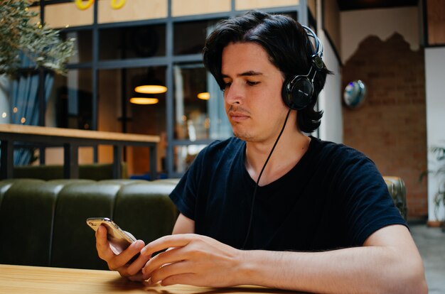 Niño sonriente escuchando música con auriculares en una cafetería.