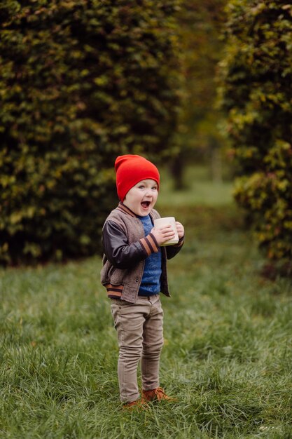 Niño sonriente feliz jugando al aire libre en un jardín.