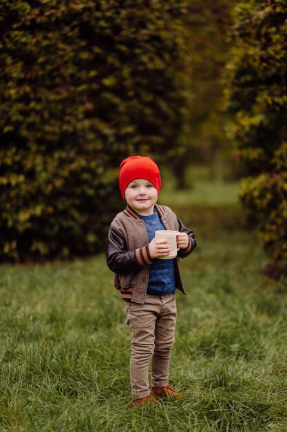 Niño sonriente feliz jugando al aire libre en un jardín.