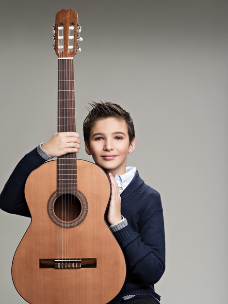 Niño sonriente con guitarra.