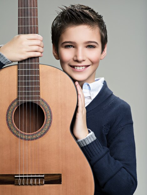 Niño sonriente con guitarra.