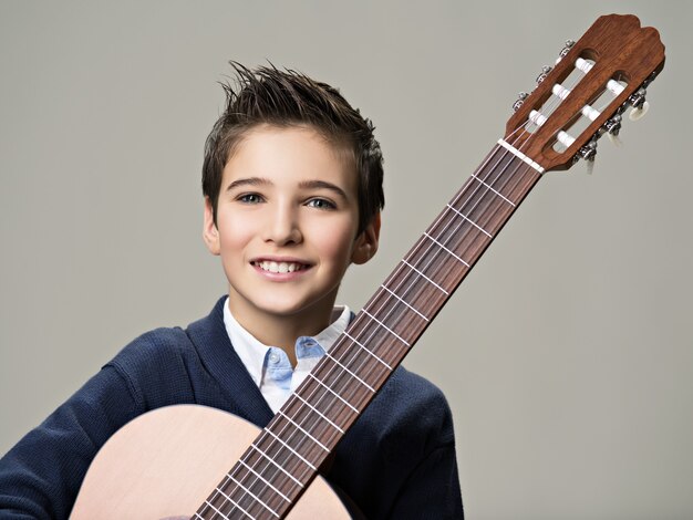 Niño sonriente con guitarra.