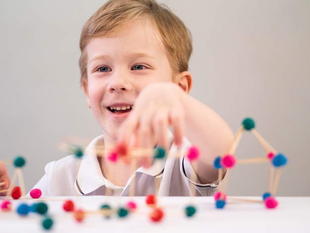 Niño sonriente jugando con coloridos átomos juego