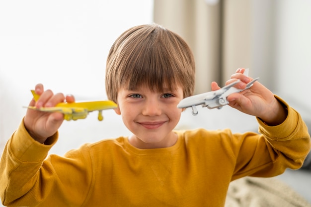 Niño sonriente jugando con figuritas de avión en casa