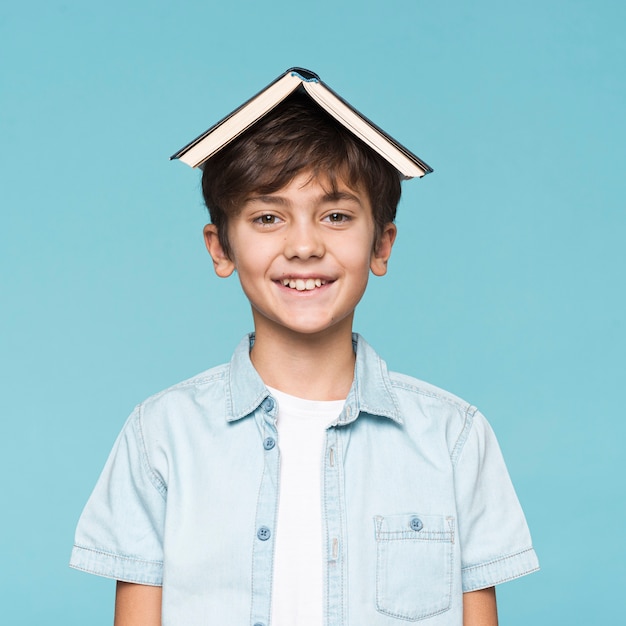 Niño sonriente con libro en cabeza