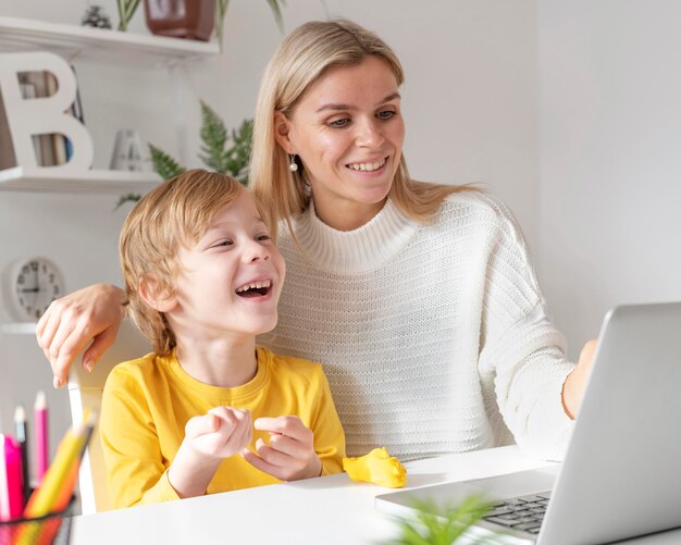 Niño sonriente y madre usando laptop en casa