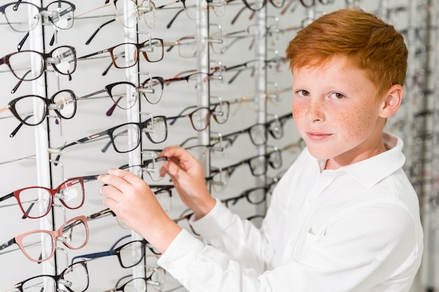 Niño sonriente mirando a la cámara mientras se quita el estante de exhibición delantero de las lentes