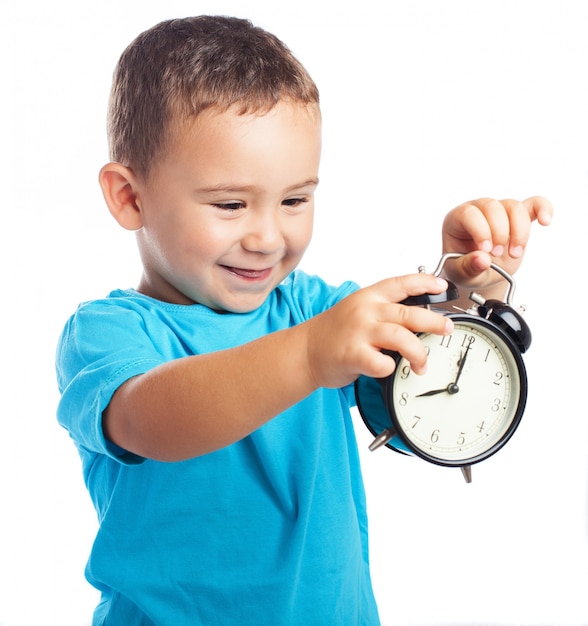 Niño sonriente mirando un reloj despertador