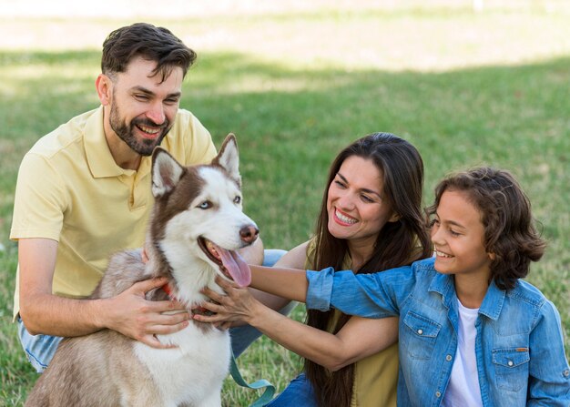 Niño sonriente y padres acariciando a un perro en el parque