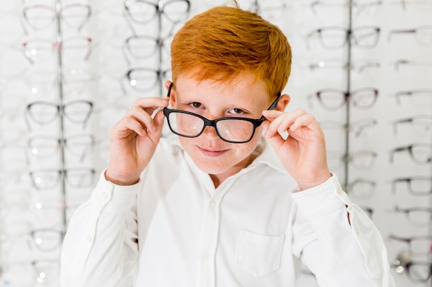 Foto gratuita niño sonriente con pecas en su rostro con gafas y mirando a cámara