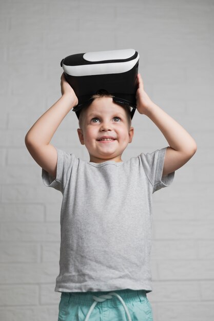 Niño sonriente poniéndose auriculares virtuales