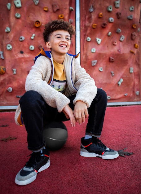 Niño sonriente posando junto a un muro de escalada