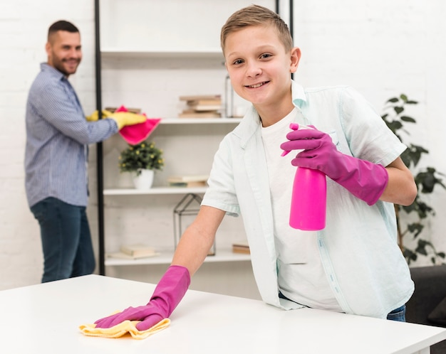 Niño sonriente posando mientras limpia con guantes de goma