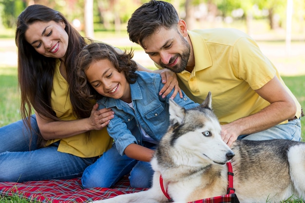 Niño sonriente posando en el parque con perro y padres