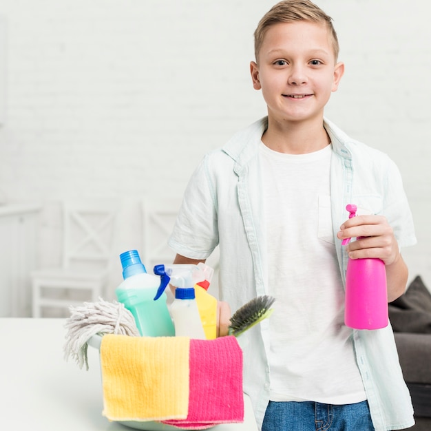 Niño sonriente posando con productos de limpieza