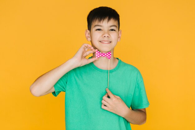 Foto gratuita niño sonriente probándose una pajarita falsa