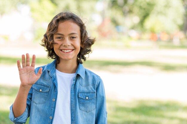 Niño sonriente saludando mientras está en el parque