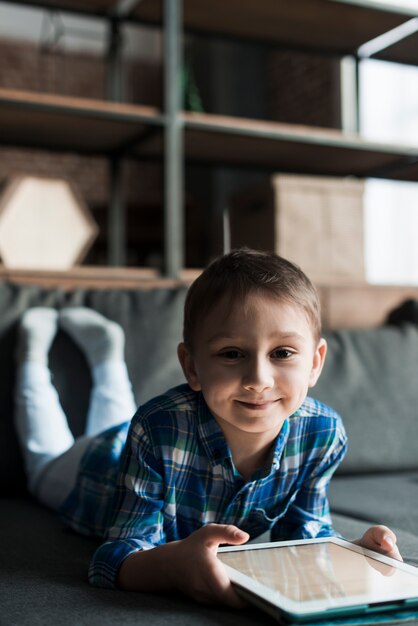 Niño sonriente en sofá con tablet