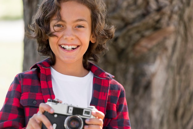 Niño sonriente sosteniendo la cámara mientras está en el parque