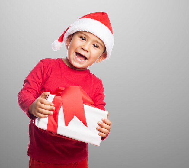 Niño sonriente sosteniendo un regalo con cinta decorativa