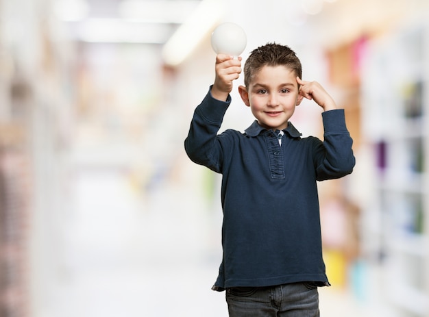 Niño sonriente sujetando una bombilla