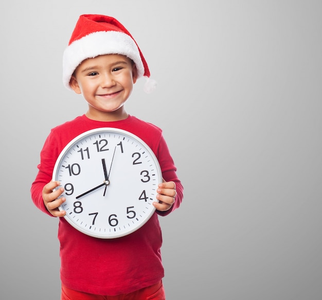 Niño sonriente sujetando un reloj