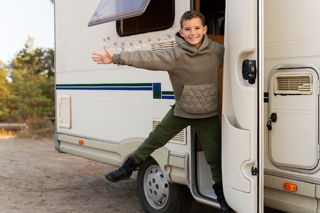 Foto gratuita niño sonriente de tiro completo en autocaravana