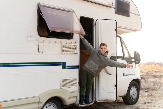 Niño sonriente de tiro completo en autocaravana