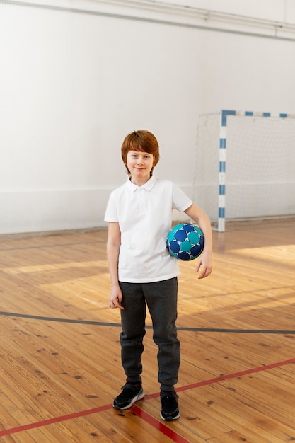 Niño sonriente de tiro completo con bola