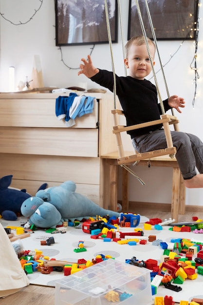 Foto gratuita niño sonriente de tiro completo en columpio en casa