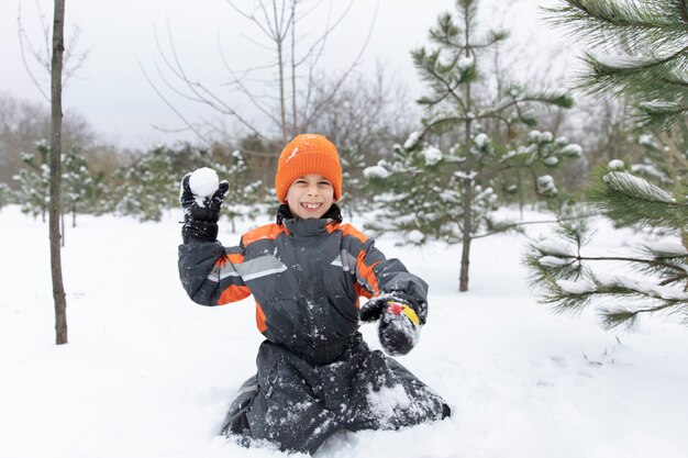 Niño sonriente de tiro completo jugando con nieve