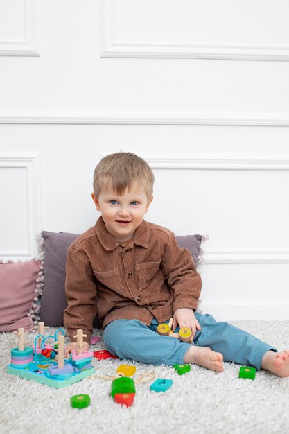 Niño sonriente de tiro completo con juguetes