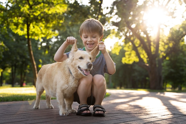 Niño sonriente de tiro completo y perro en el parque